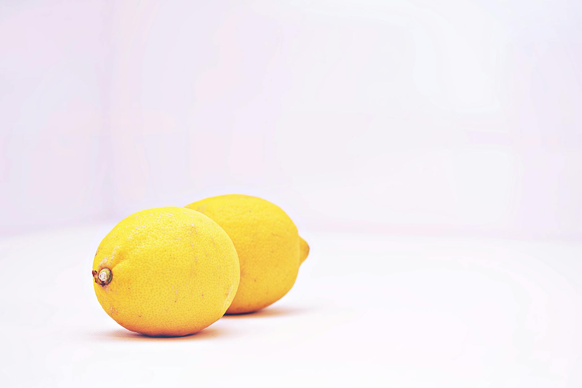 Hand holding a fresh lemon against a vibrant yellow background, representing clarity and fresh solutions to clitoral sensitivity