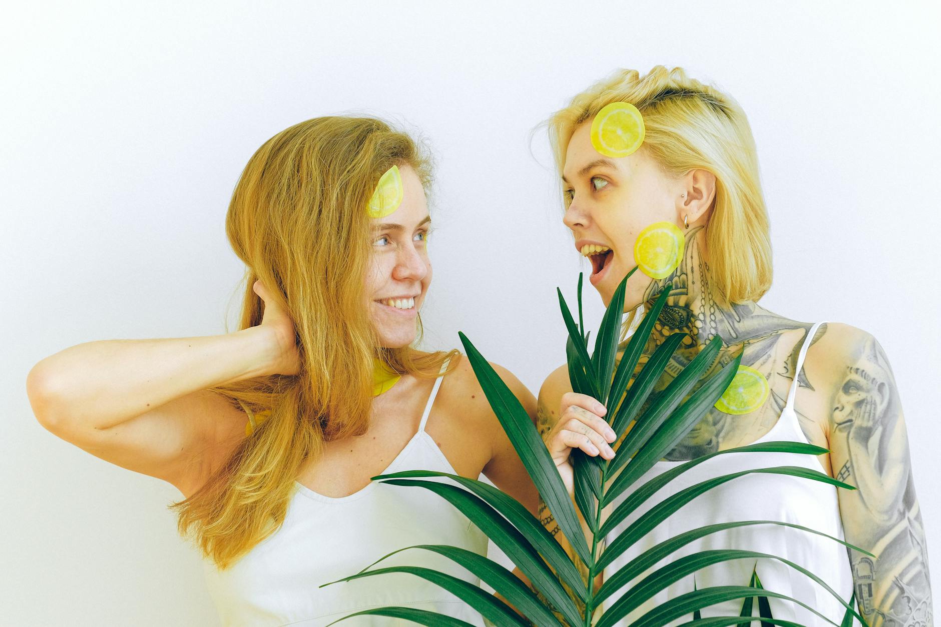 Two women laughing together with fresh lemons, expressing joy and comfort with bodies changing over time