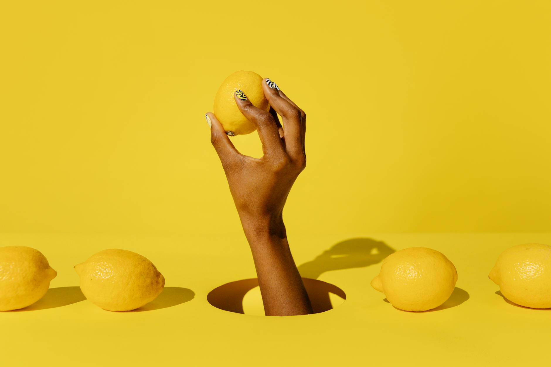 Hand holding a fresh lemon on bright yellow background, symbolizing fresh starts and renewed connection