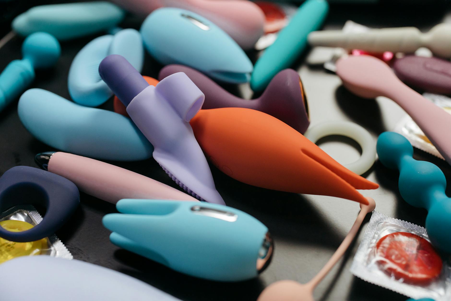 Close-up arrangement of colorful adult toys including vibrators designed for clitoral stimulation
