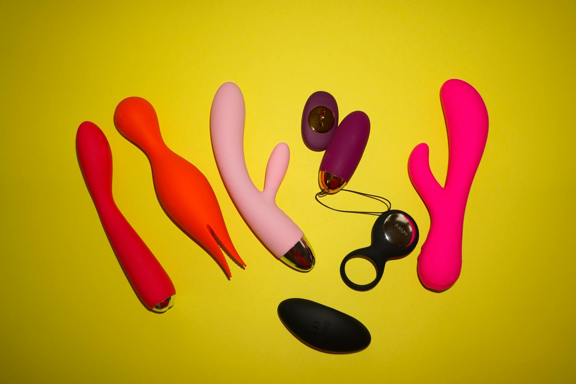 Vibrant display of silicone clitoral vibrators on dark fabric showing various colors and shapes