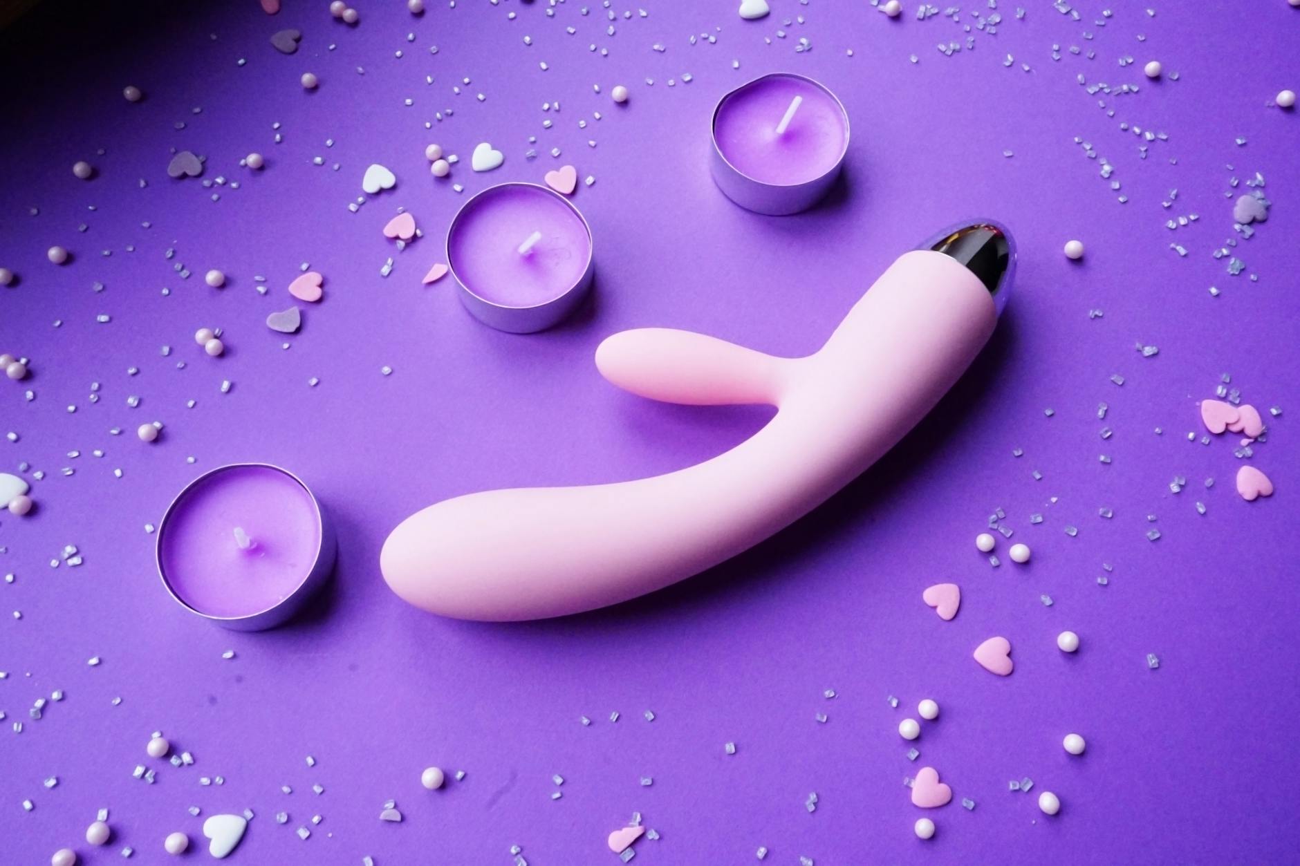 A couple standing close together indoors, exploring intimacy together with modern toys